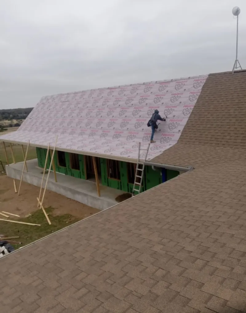 Worker preparing underlayment for a metal roof installation in Belle Glade